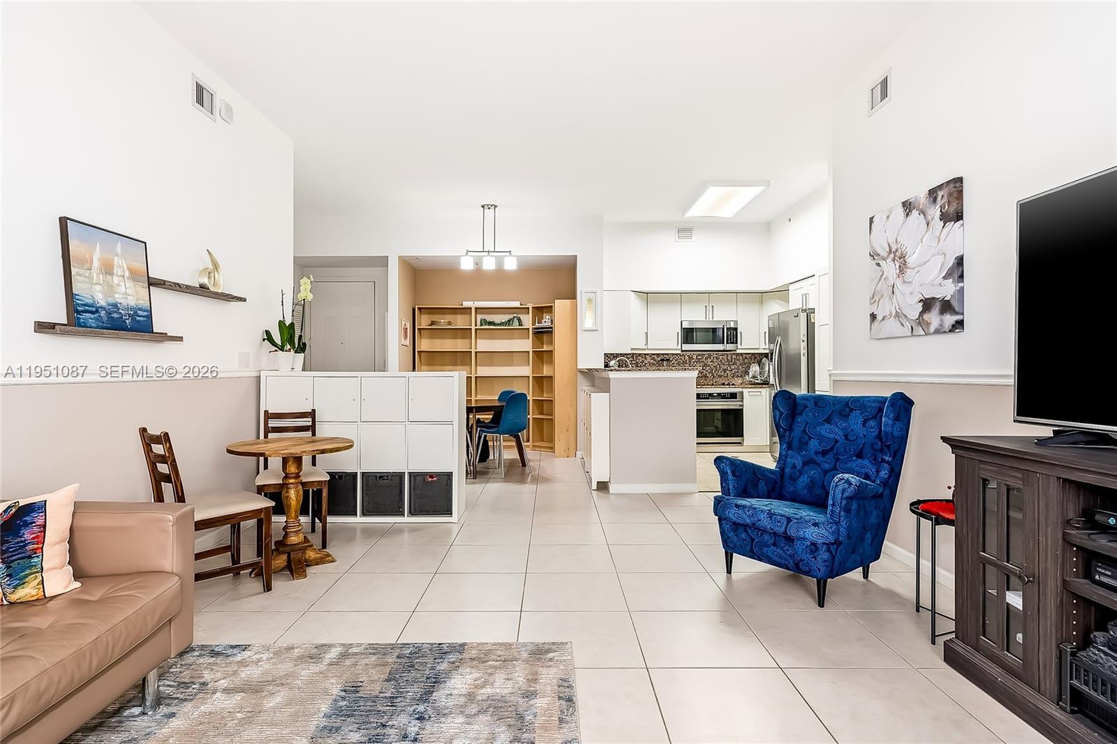 An open-concept living area features a kitchen, dining space, and a blue armchair — 2080 S Ocean Dr # 103, Hallandale Beach FL 33009, HALLANDALE BEACH, FL
