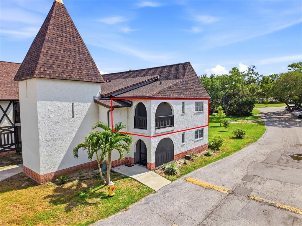 An exterior view of a two-story building featuring arched balconies and a shingled roof — 316 N BAYSHORE BOULEVARD UNIT 208, CLEARWATER, FL