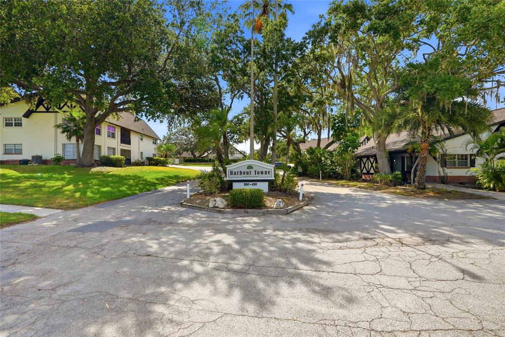 A sign for Harbour Towne Condominiums stands at the entrance of a tree-lined residential complex — 316 N BAYSHORE BOULEVARD UNIT 208, CLEARWATER, FL
