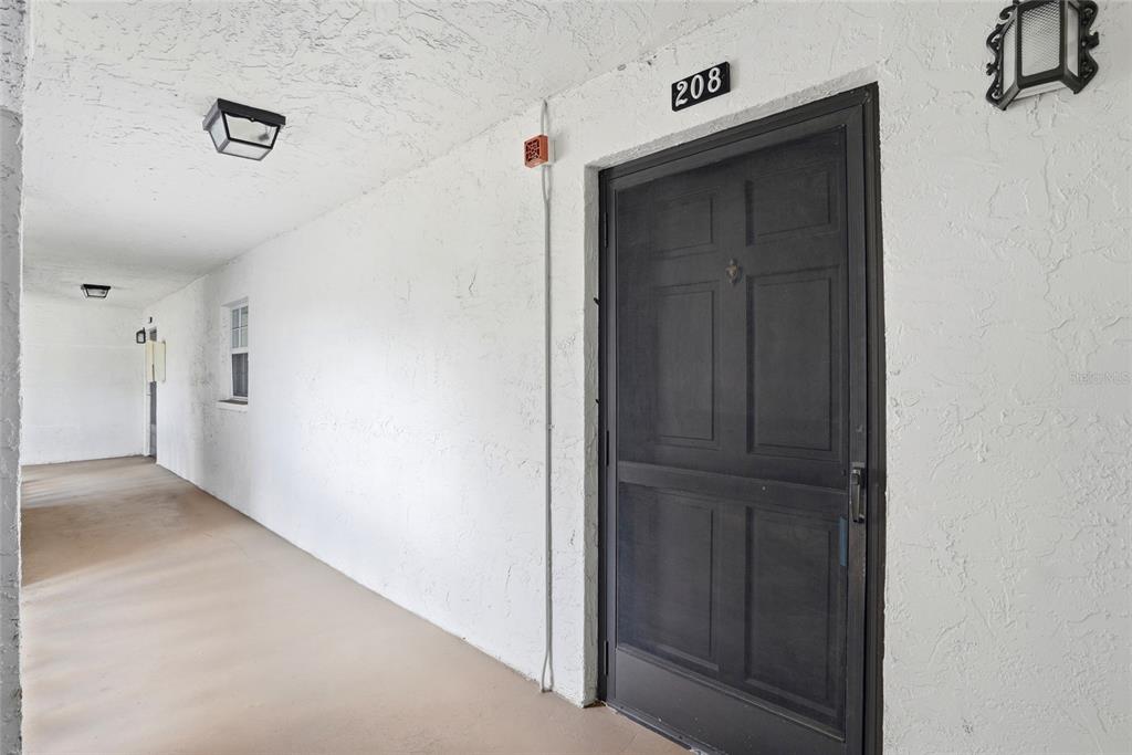 A dark screen door with the number 208 is set in a white stucco wall — 316 N BAYSHORE BOULEVARD UNIT 208, CLEARWATER, FL