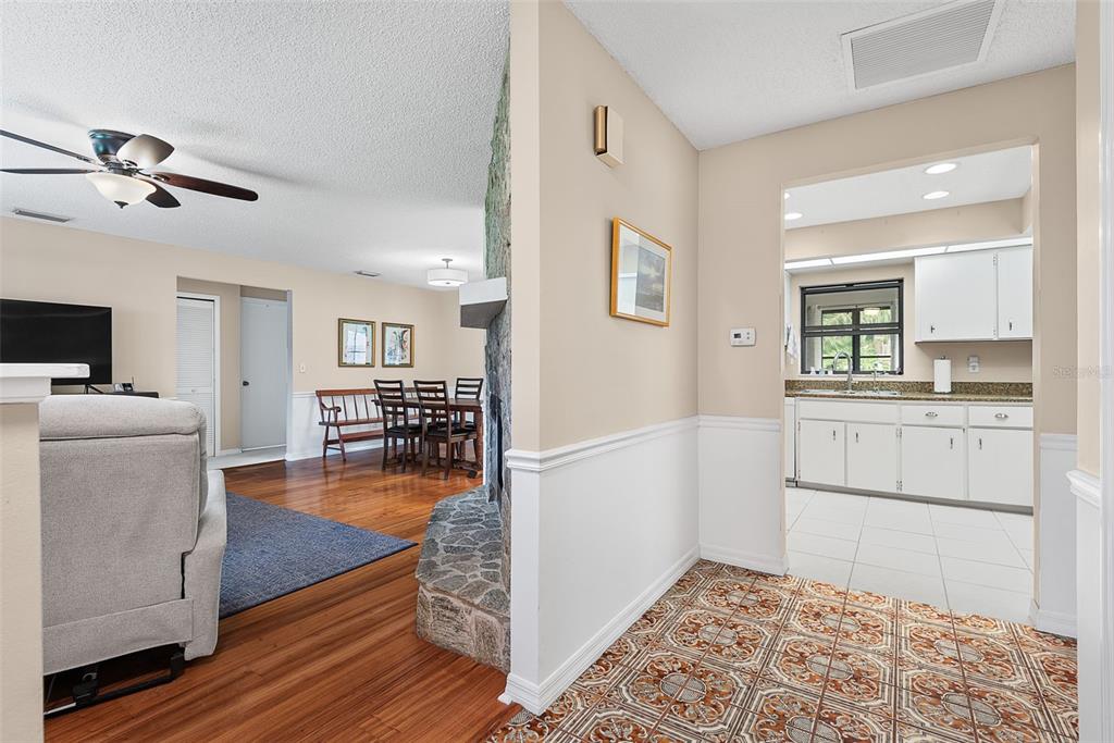 A view from a tiled entryway looking into a living room and a white kitchen — 49 BANNERWOOD LANE, PALM COAST, FL