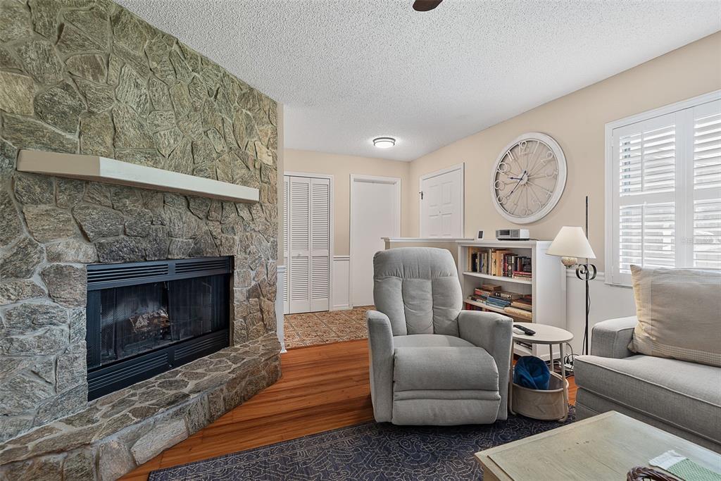 A living room features a stone fireplace, wood flooring, a recliner, and a bookshelf — 49 BANNERWOOD LANE, PALM COAST, FL
