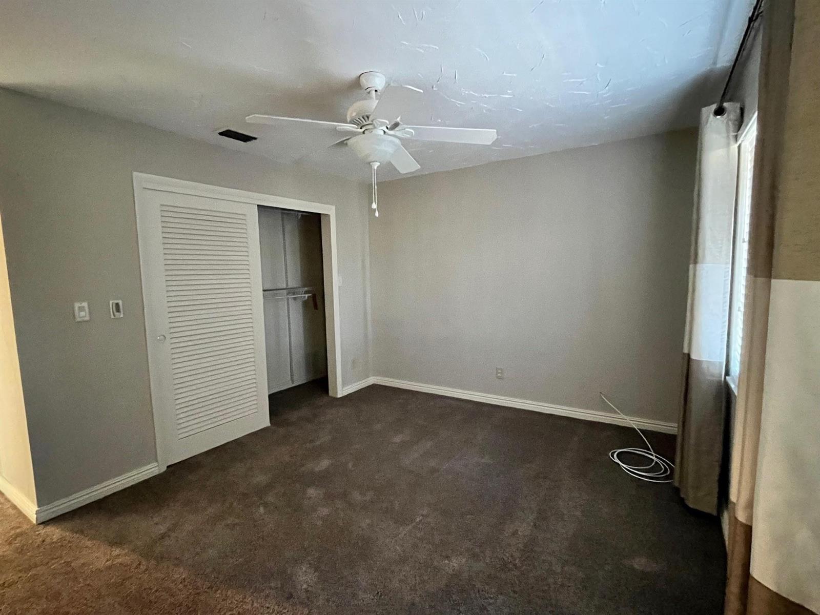 A bedroom with gray walls, brown carpet, a ceiling fan, and a sliding closet door — 3040 NW 1st Avenue, Pompano Beach FL 33064, POMPANO BEACH, FL