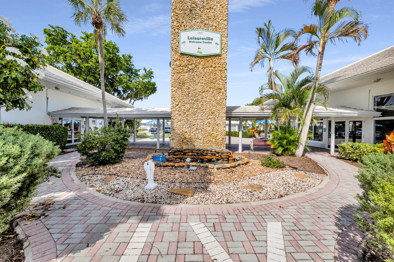 The exterior of a community welcome center features a stone pillar, fountain, and palm trees — 3040 NW 1st Avenue, Pompano Beach FL 33064, POMPANO BEACH, FL