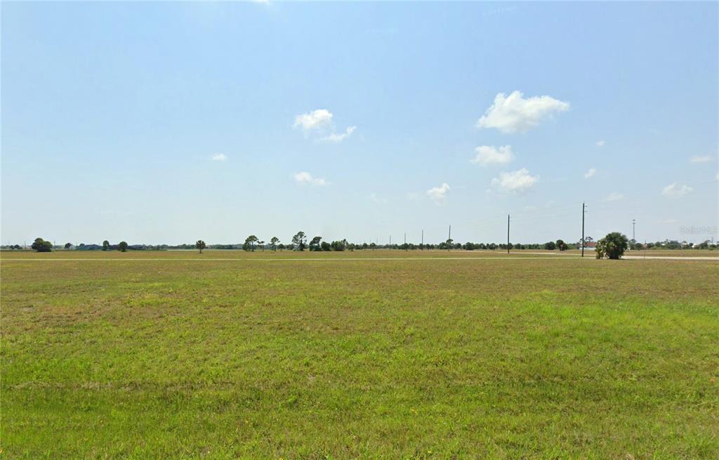 A wide, flat, grassy field under a bright blue sky with scattered clouds — 54 REDWOOD DRIVE, PLACIDA, FL