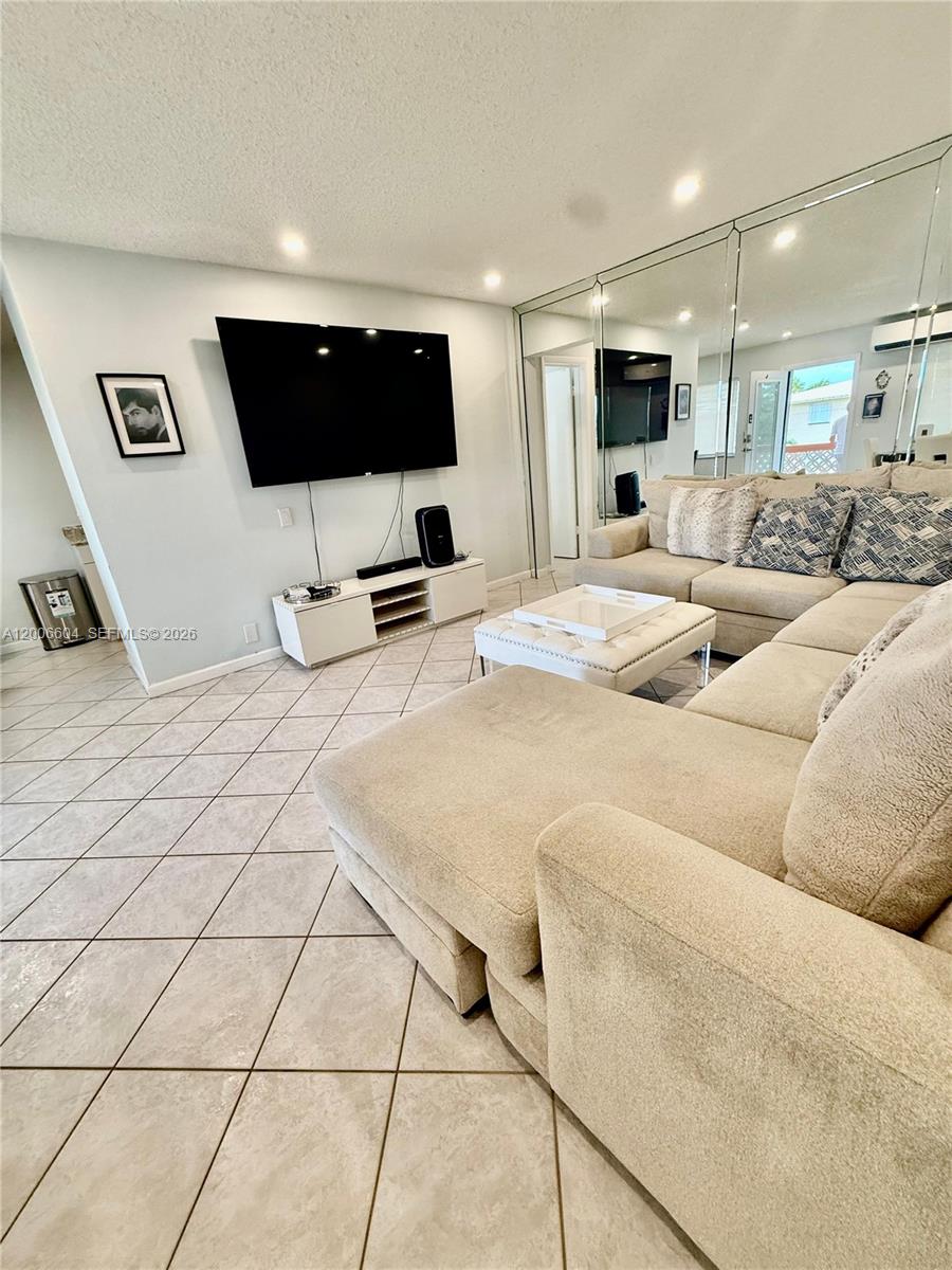A living room features a large sectional sofa, a wall-mounted television, and mirrored walls — 800 SW 11th Ave # 19A, Hallandale Beach FL 33009, HALLANDALE BEACH, FL