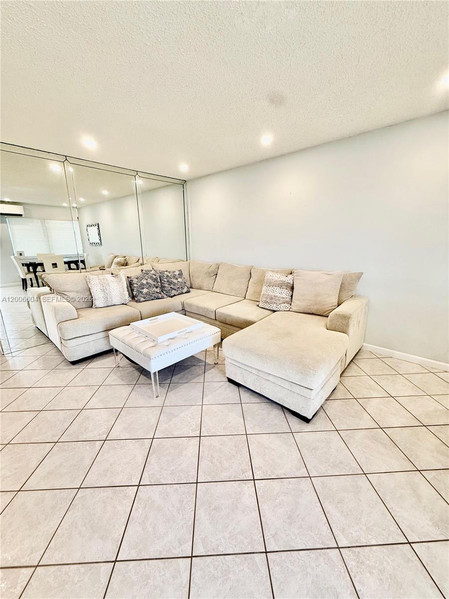 A living room features a large beige sectional sofa, a tufted ottoman, and mirrored walls — 800 SW 11th Ave # 19A, Hallandale Beach FL 33009, HALLANDALE BEACH, FL