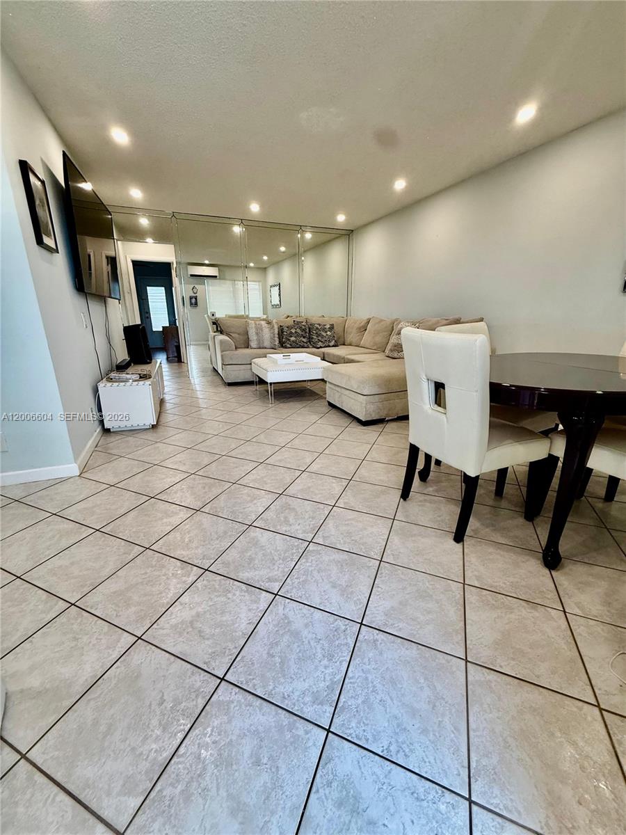 A living and dining area features light-colored tile flooring, a sectional sofa, and mirrored walls — 800 SW 11th Ave # 19A, Hallandale Beach FL 33009, HALLANDALE BEACH, FL
