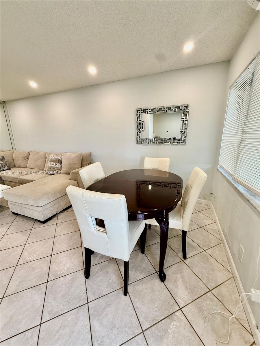 A dining area features a dark wood table, four white chairs, and a wall mirror — 800 SW 11th Ave # 19A, Hallandale Beach FL 33009, HALLANDALE BEACH, FL