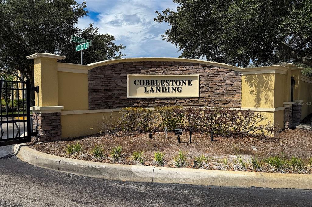 A stone and stucco monument sign marks the entrance to the Cobblestone Landing community — 5359 RIVER ROCK ROAD, LAKELAND, FL