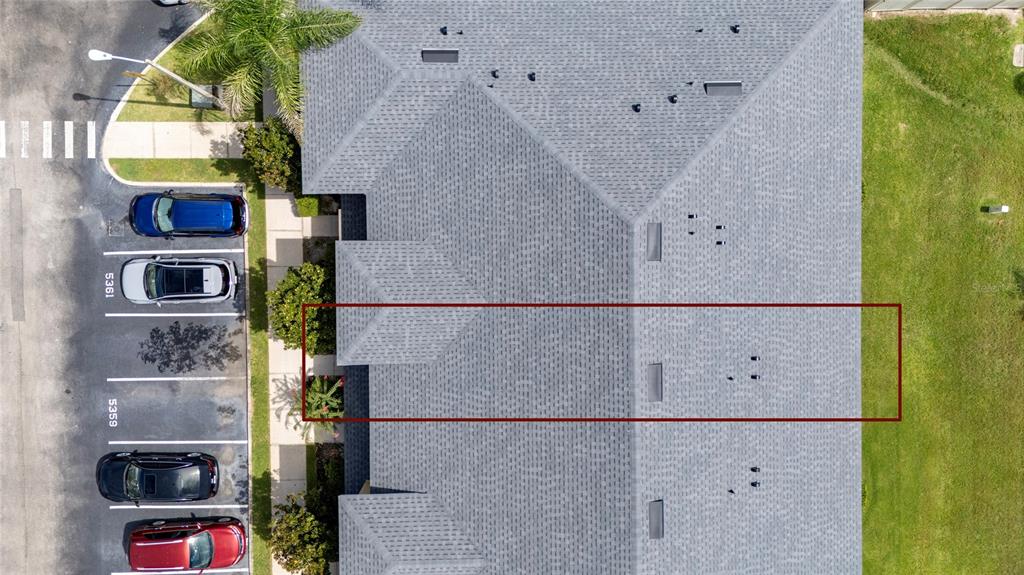 An aerial view shows the gray shingled roof of a residential building with parking spaces — 5359 RIVER ROCK ROAD, LAKELAND, FL
