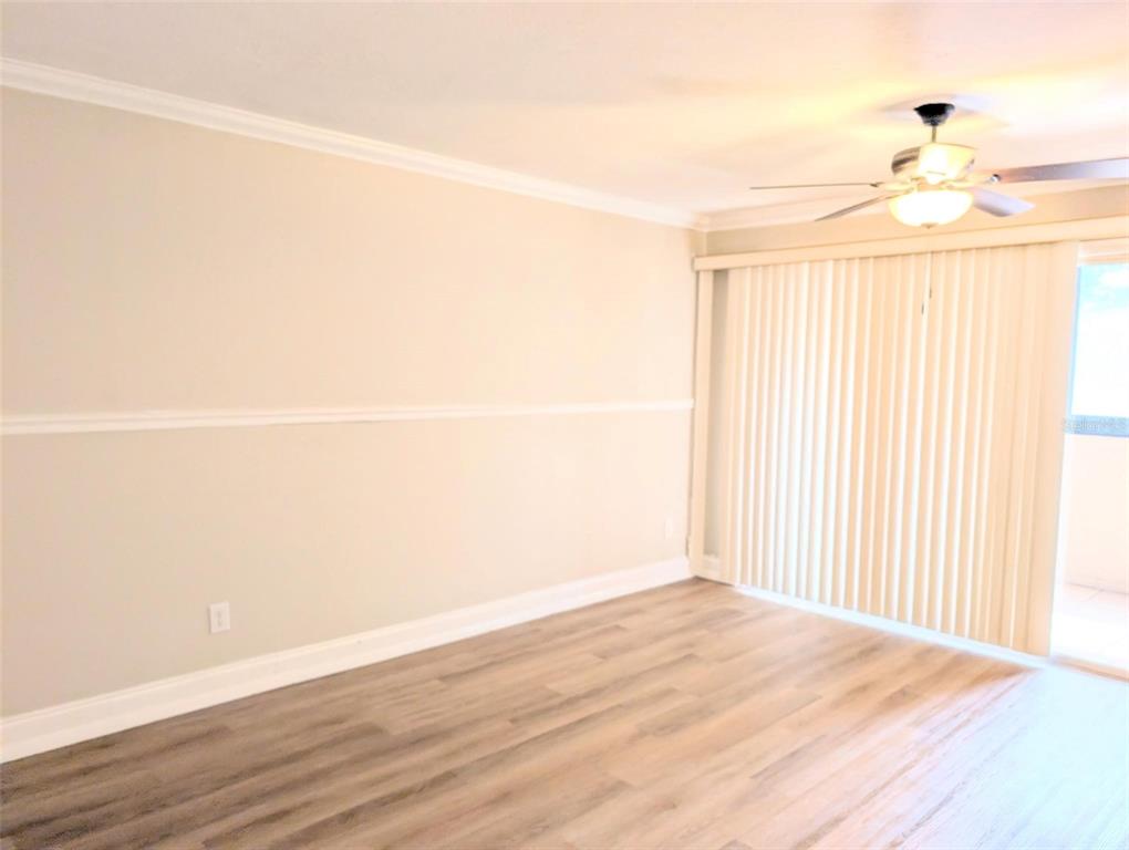 An empty room with light-colored walls, chair rail molding, wood-look flooring, and vertical window blinds — 3700 S OSPREY AVENUE UNIT 212, SARASOTA, FL