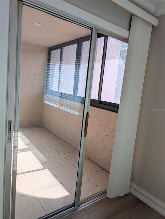 A sliding glass door opens to a tiled, enclosed balcony with windows and blinds — 3700 S OSPREY AVENUE UNIT 212, SARASOTA, FL