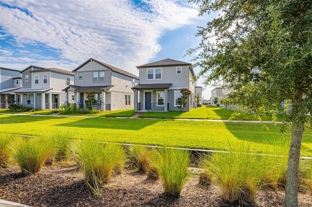 A row of modern two-story suburban houses sits behind a grassy lawn and landscaping — 4629 CROSS PRAIRIE PARKWAY, ST CLOUD, FL