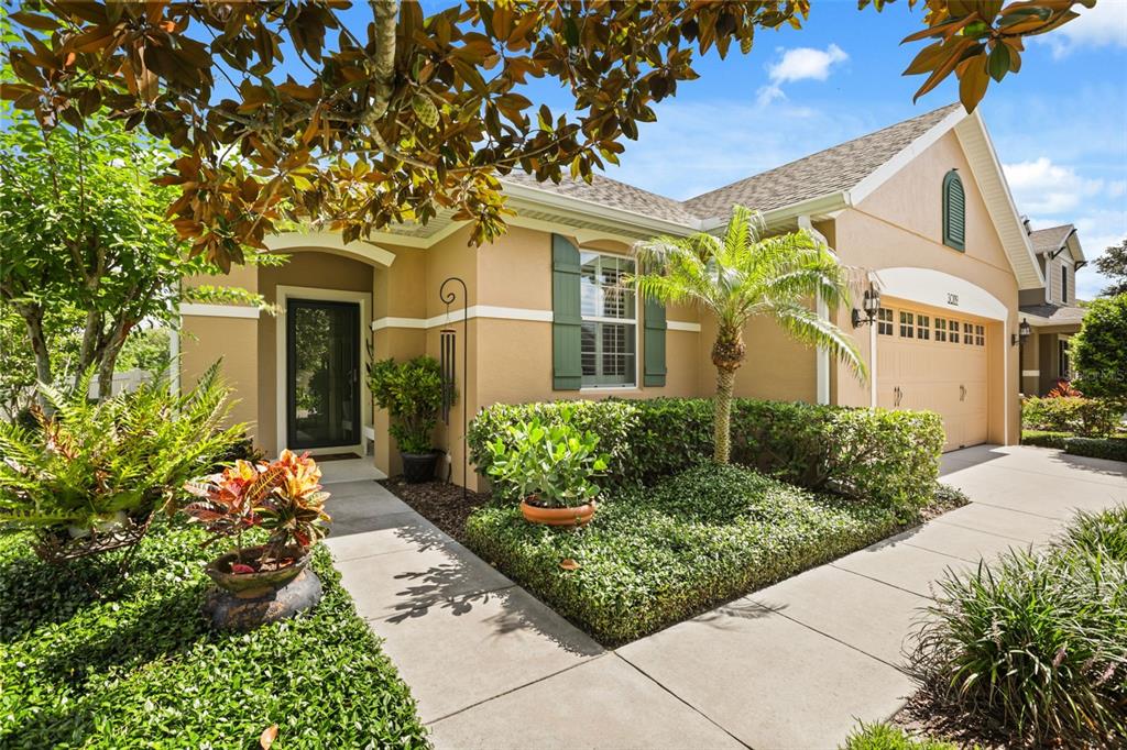 A tan single-story house with green shutters, a two-car garage, and landscaped front yard — 30119 TOKARA TERRACE, MOUNT DORA, FL
