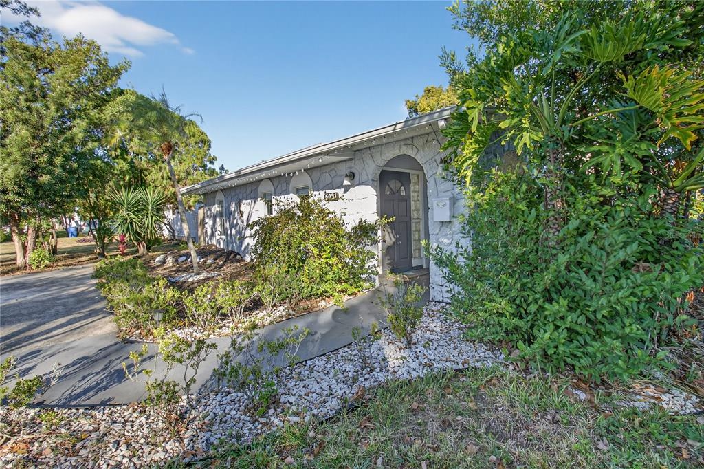 A stone-faced house exterior features a dark front door, a walkway, and surrounding landscaping — 5021 37TH AVENUE N, ST PETERSBURG, FL