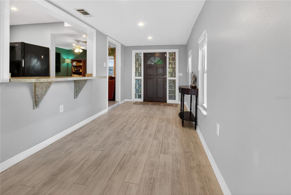 A dining area with wood-look flooring, a breakfast bar, and a dark wood front door — 5021 37TH AVENUE N, ST PETERSBURG, FL