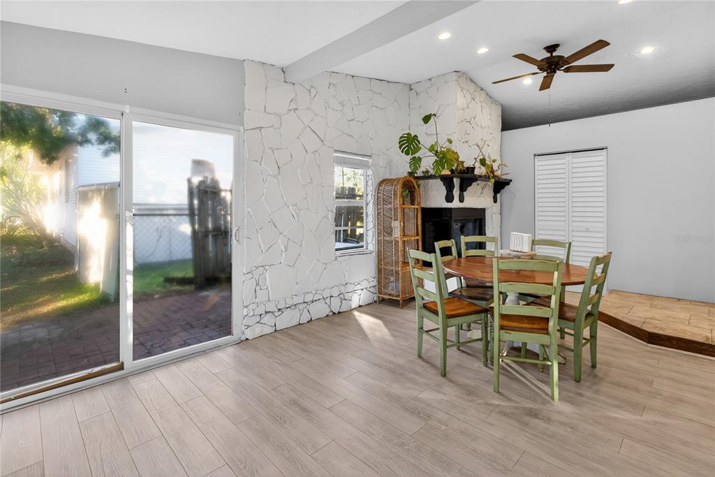 A dining area features light wood flooring, a white stone fireplace, and a sliding glass door — 5021 37TH AVENUE N, ST PETERSBURG, FL