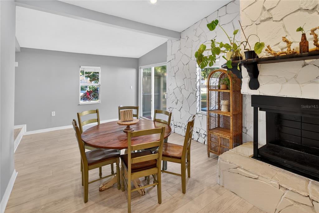 A dining area features a round wooden table, chairs, and a white stone fireplace — 5021 37TH AVENUE N, ST PETERSBURG, FL