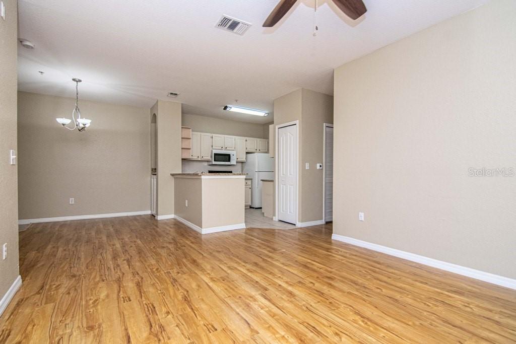 An open-concept living and dining area features wood-look flooring and a kitchen with white cabinets — 5713 LEGACY CRESCENT PLACE UNIT 101, RIVERVIEW, FL