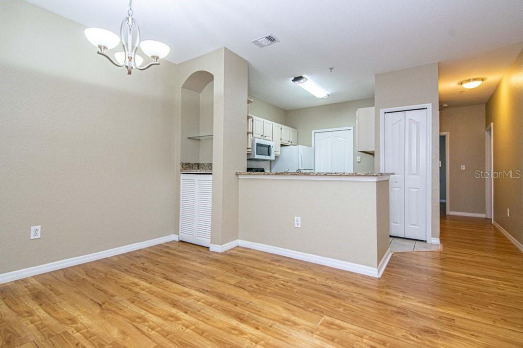 A dining area with wood-look flooring, a chandelier, and an open kitchen with granite countertops — 5713 LEGACY CRESCENT PLACE UNIT 101, RIVERVIEW, FL