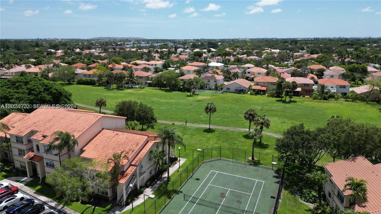 An aerial view shows a tennis court, a large grassy field, and residential buildings — 3420 N Pinewalk Dr N # 717, Margate FL 33063, MARGATE, FL