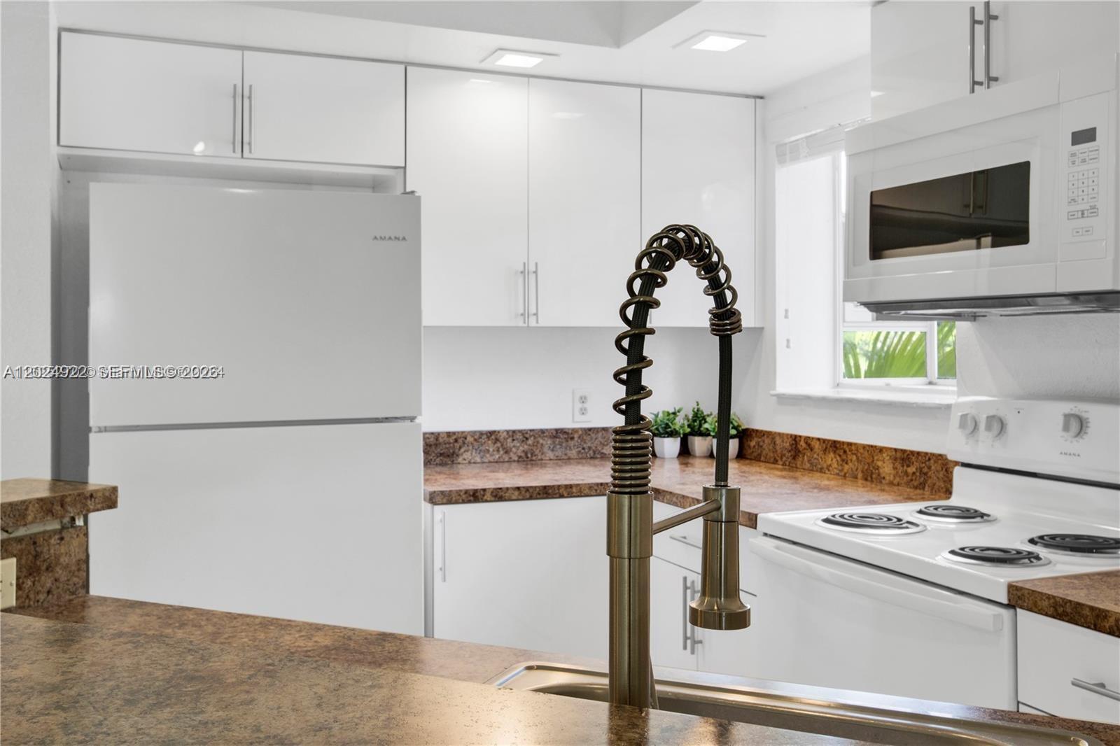 A kitchen features white cabinets, a white refrigerator, a white stove, and brown countertops — 3420 N Pinewalk Dr N # 717, Margate FL 33063, MARGATE, FL