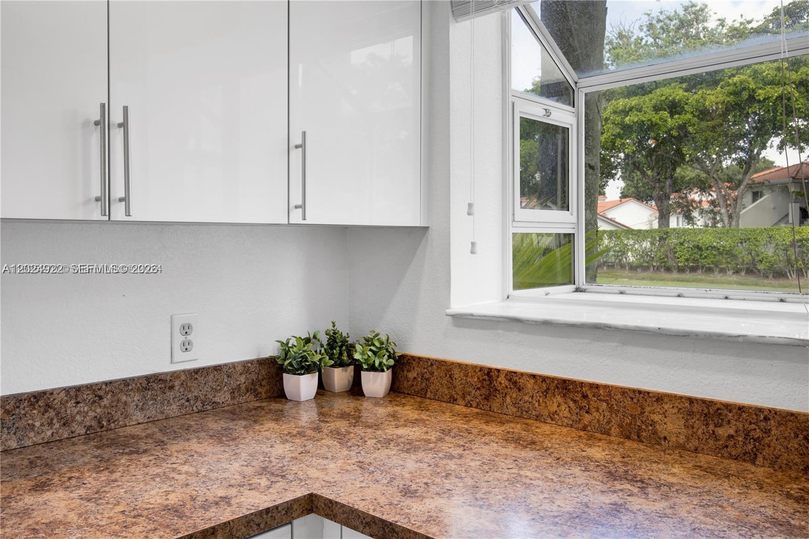 A kitchen corner features brown speckled countertops, white cabinets, and a garden window — 3420 N Pinewalk Dr N # 717, Margate FL 33063, MARGATE, FL