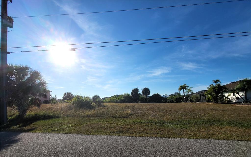 A vacant, grassy residential lot is viewed from the street under a bright sun — 9620 PRESIDENT CIRCLE, PORT CHARLOTTE, FL