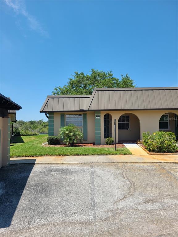 A single-story building with a brown metal roof, arched entryways, and a paved parking area — 4120 STRATFORD DRIVE, NEW PORT RICHEY, FL