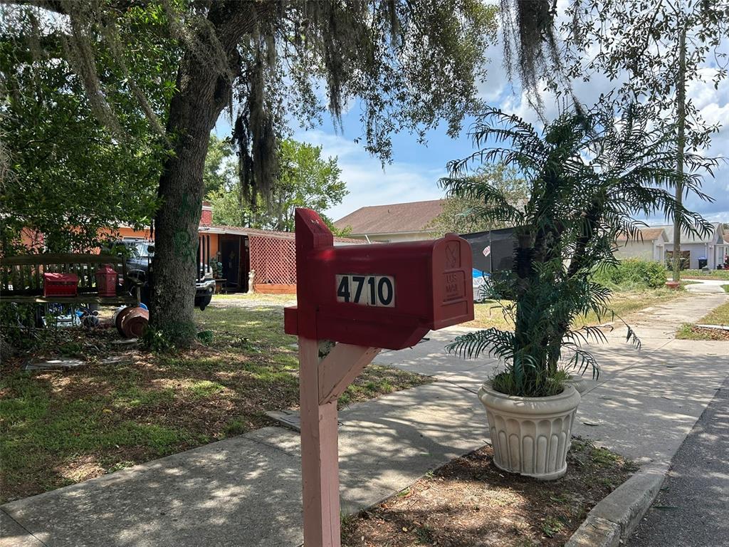 A red mailbox with the number 4710 stands on a post near a sidewalk — 4710 ROBBINS AVENUE, ORLANDO, FL