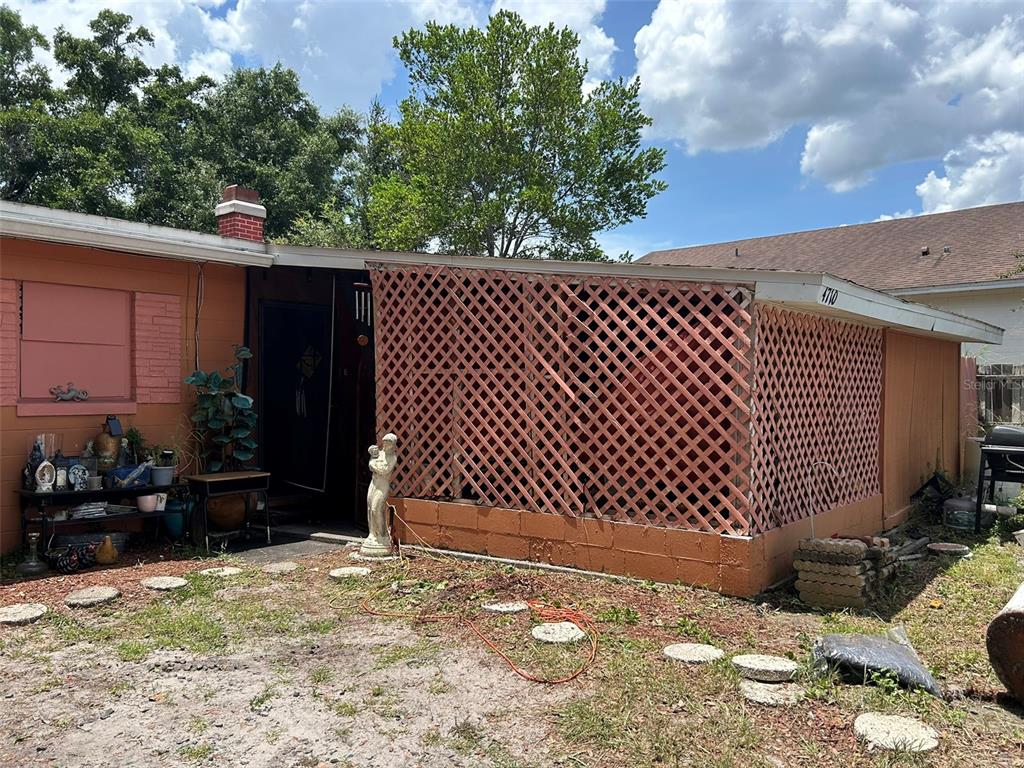 The exterior of a house features a lattice-enclosed porch and a small front yard — 4710 ROBBINS AVENUE, ORLANDO, FL