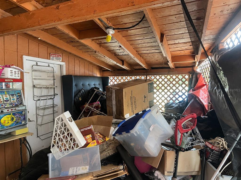 A cluttered, unfinished storage shed with exposed wooden rafters, a light bulb, and various boxes — 4710 ROBBINS AVENUE, ORLANDO, FL