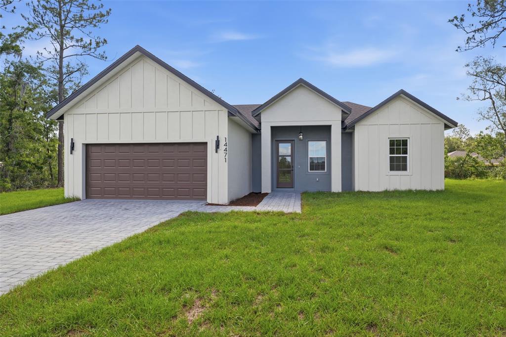 A single-story house with white vertical siding, a brown garage door, and a paved driveway — 14471 SW 61ST COURT, OCALA, FL