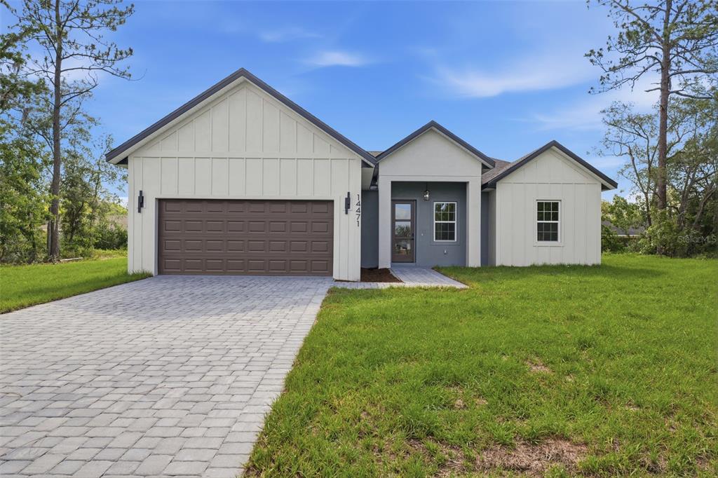 A single-story house with a white board-and-batten exterior, a two-car garage, and a paved driveway — 14471 SW 61ST COURT, OCALA, FL