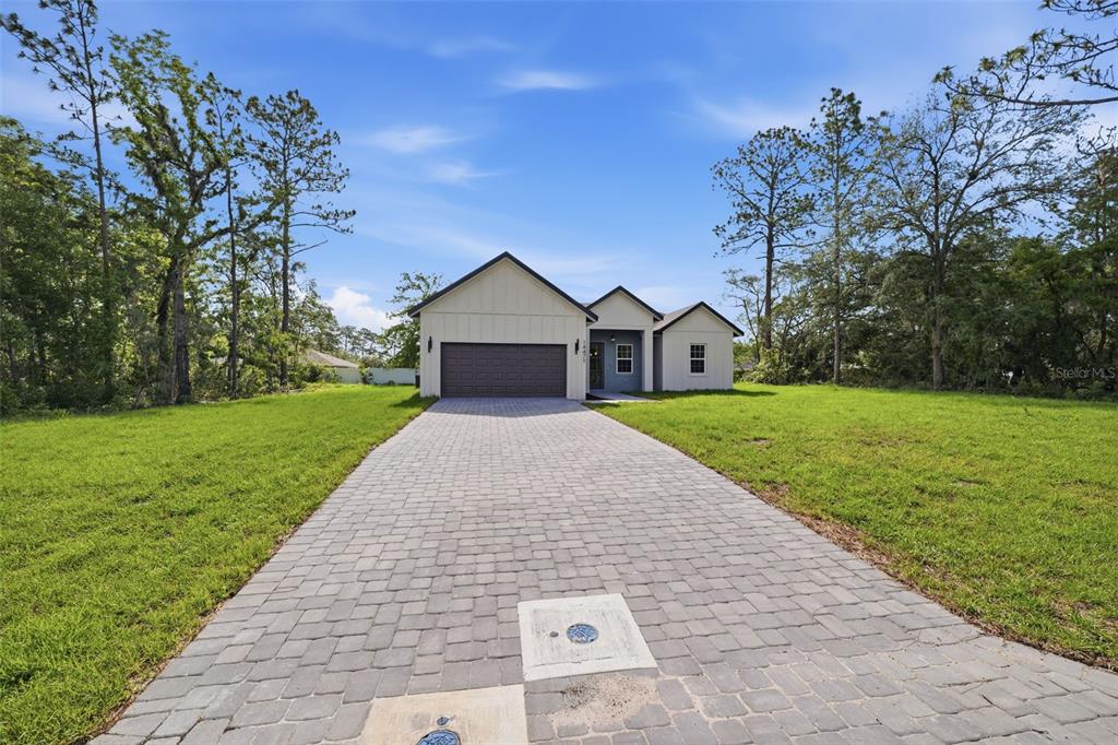 A single-story house with a paved driveway and a two-car garage sits on a grassy lot — 14471 SW 61ST COURT, OCALA, FL