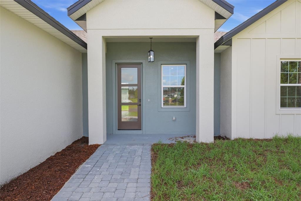 A paved walkway leads to the front entrance of a house with a glass-paneled door — 14471 SW 61ST COURT, OCALA, FL