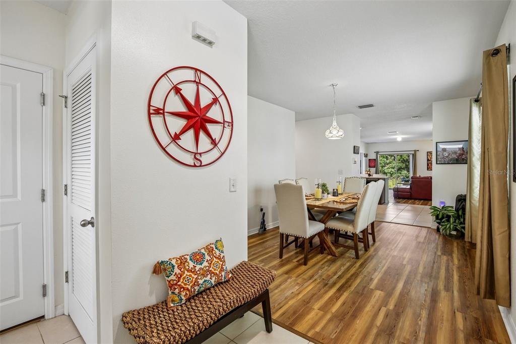 A dining area with a wooden table and chairs sits adjacent to a foyer bench — 11008 LELAND GROVES DRIVE, RIVERVIEW, FL