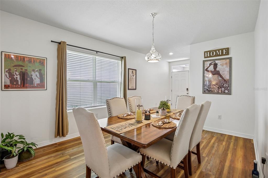 A dining room features a wooden table, upholstered chairs, a pendant light, and wall art — 11008 LELAND GROVES DRIVE, RIVERVIEW, FL