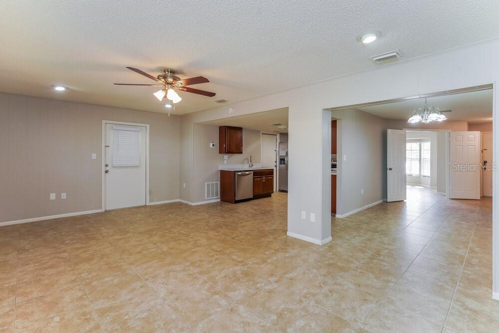 An open-concept living area with tile flooring leads into a kitchen with dark wood cabinets — 403 BLUEBERRY DRIVE, EUSTIS, FL