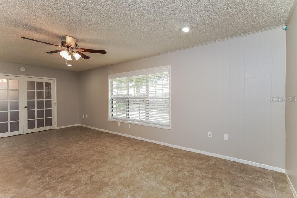 A living room features light gray walls, tile flooring, a ceiling fan, and French doors — 403 BLUEBERRY DRIVE, EUSTIS, FL
