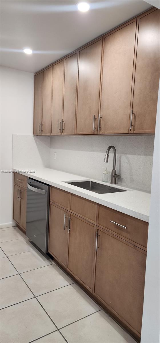 A kitchen features light-colored countertops, wood-toned cabinets, a stainless steel dishwasher, and tile flooring — 500 NE 2nd St # 213, Dania Beach FL 33004, DANIA BEACH, FL