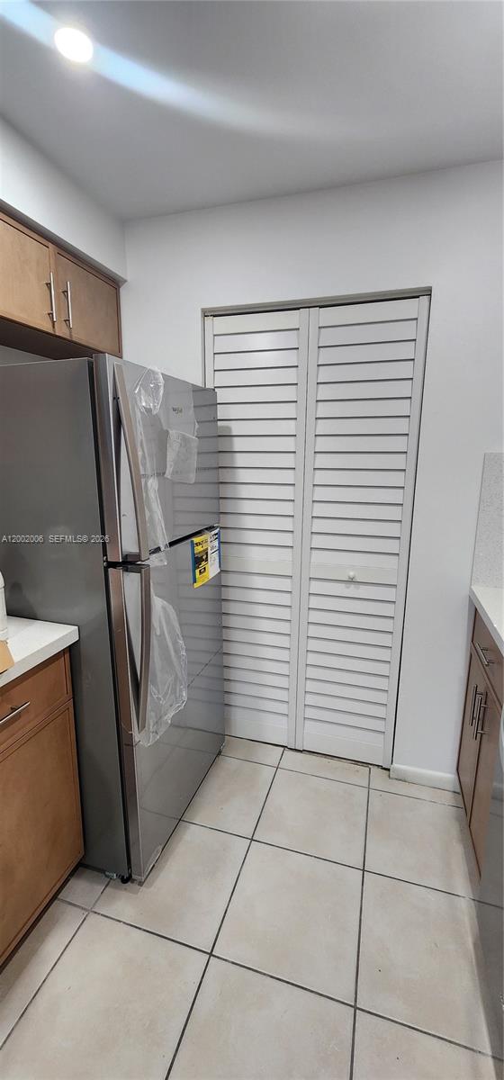 A kitchen features a stainless steel refrigerator, wooden cabinets, and white louvered closet doors — 500 NE 2nd St # 213, Dania Beach FL 33004, DANIA BEACH, FL