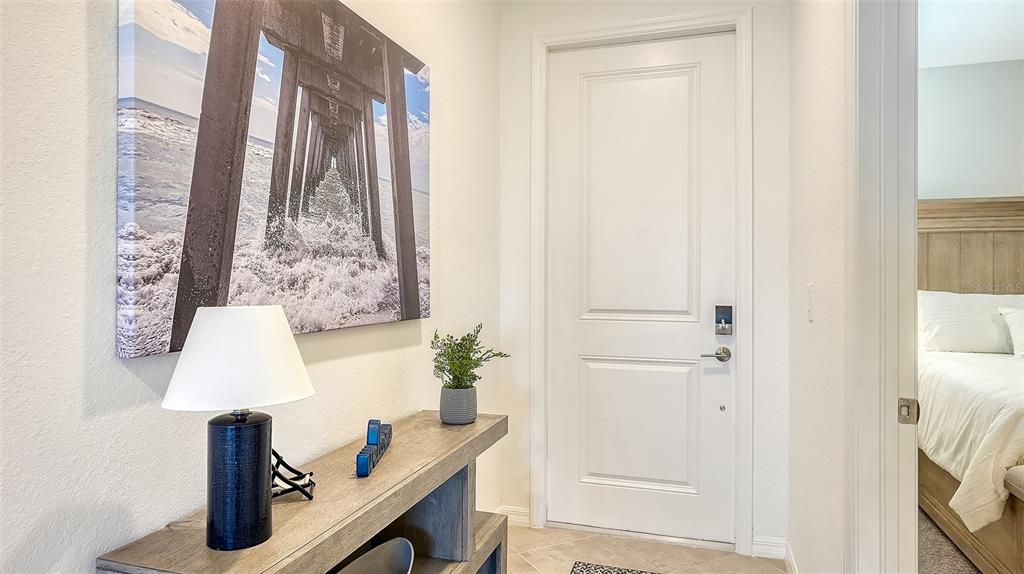 A hallway features a wooden console table, a lamp, wall art, and a white door — 12140 WELLEN GOLF STREET UNIT 203, VENICE, FL