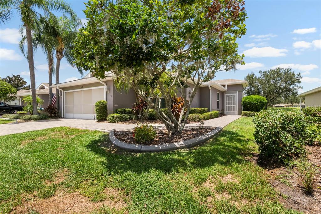 A single-story house with a paved driveway, a garage, and a landscaped front yard — 1148 CORINTH GREENS DRIVE, SUN CITY CENTER, FL