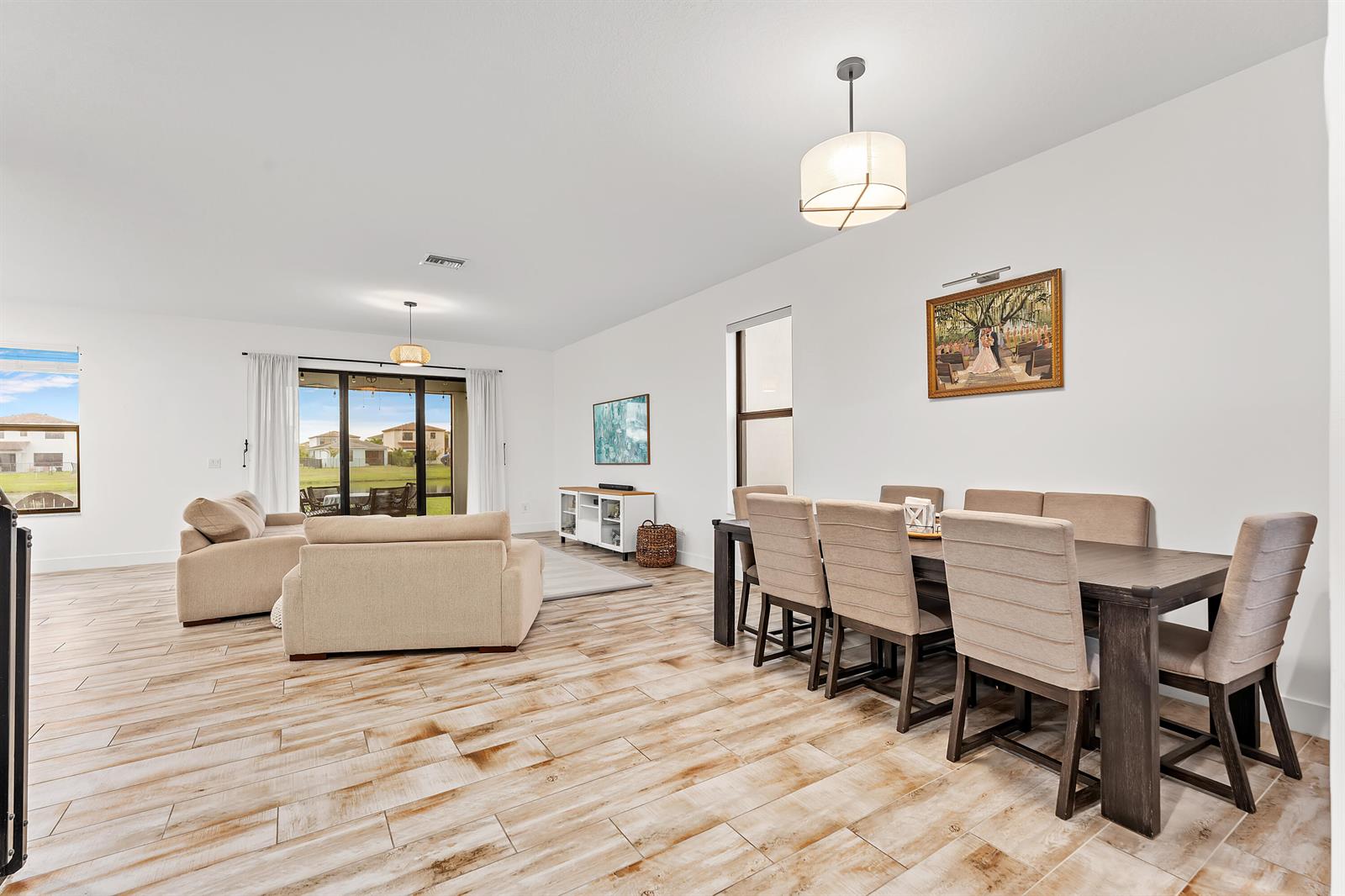 An open-concept living and dining area features light wood-look tile flooring and neutral furniture — 16235 Sandy Shore Drive, Westlake FL 33470, WESTLAKE, FL