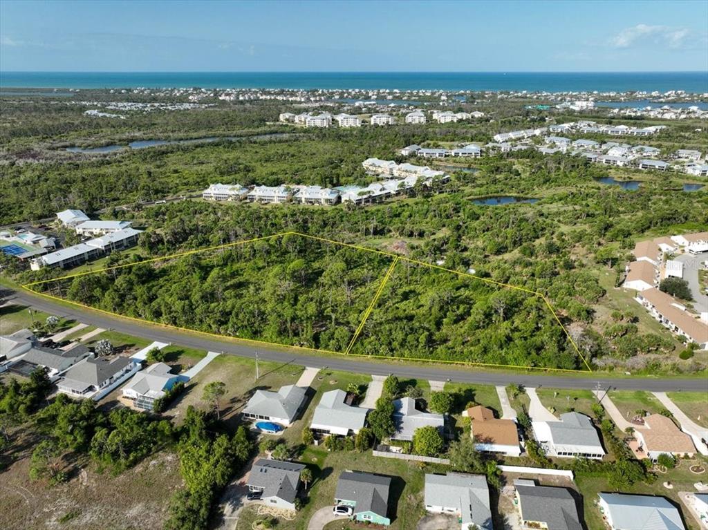 An aerial view shows two adjacent, undeveloped wooded lots bordered by a road and houses — 6700-6730 GASPARILLA PINES BOULEVARD, ENGLEWOOD, FL