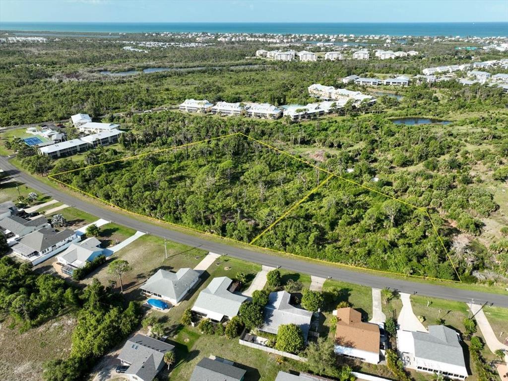 An aerial view shows two adjacent wooded lots outlined in yellow along a paved road — 6700-6730 GASPARILLA PINES BOULEVARD, ENGLEWOOD, FL