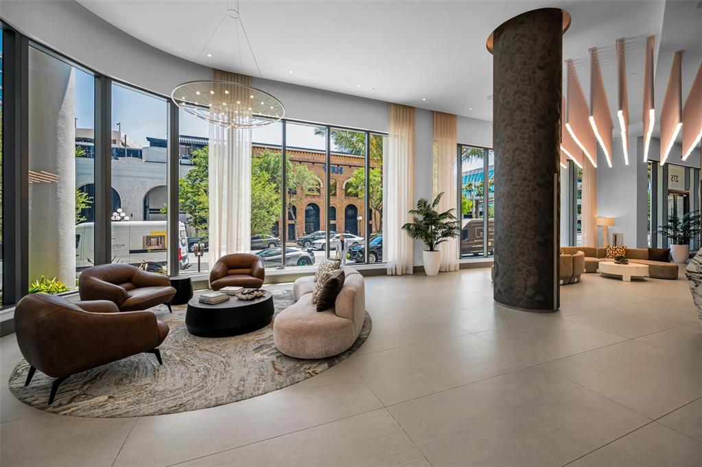 A modern lobby features floor-to-ceiling windows, a large circular rug, and a textured stone pillar — 275 1ST AVENUE S UNIT 3503, ST PETERSBURG, FL