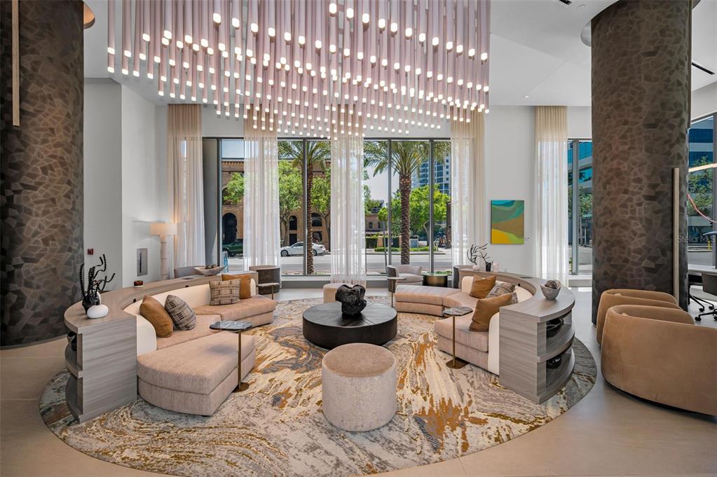 A modern lobby features a large circular seating area, a statement light fixture, and floor-to-ceiling windows — 275 1ST AVENUE S UNIT 3503, ST PETERSBURG, FL